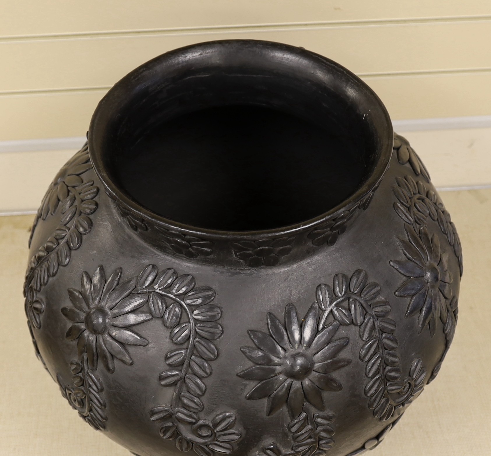 A large black-painted floral decorated terracotta vase, 50cm